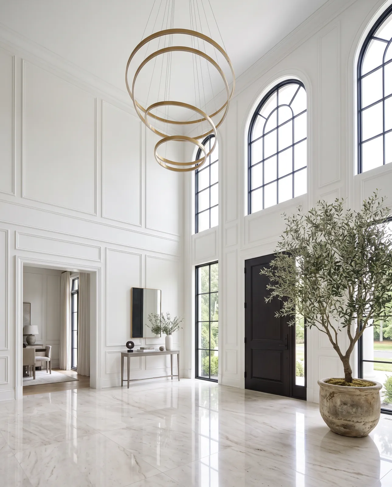 Double-height foyer with arched windows and a gold ring chandelier